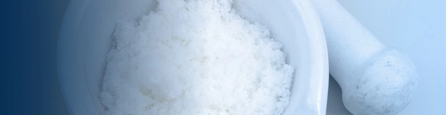 Close-up of a mortar and pestle with white powder inside, on a light blue background.
