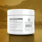 A white plastic jar of testosterone cream shown from the back, displaying the supplement facts label, against a reflective gold background.
