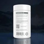 A white plastic supplement bottle shown from the back, featuring a detailed black and gray label with 'SUGGESTED USE', a QR code, a barcode, and a 'GMP' seal, set against a dark blue gradient background with a reflection below.