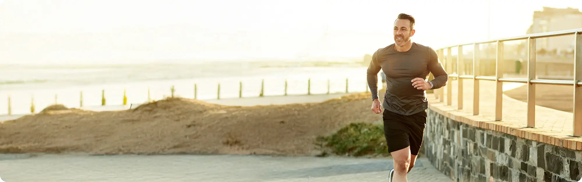 Man running along a waterfront pathway with a scenic view.